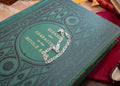 A silver-toned metal chain bracelet with a central heart-shaped link design, displayed on the cover of a vintage green book titled 'Scenes and Characters of the Middle Ages'.