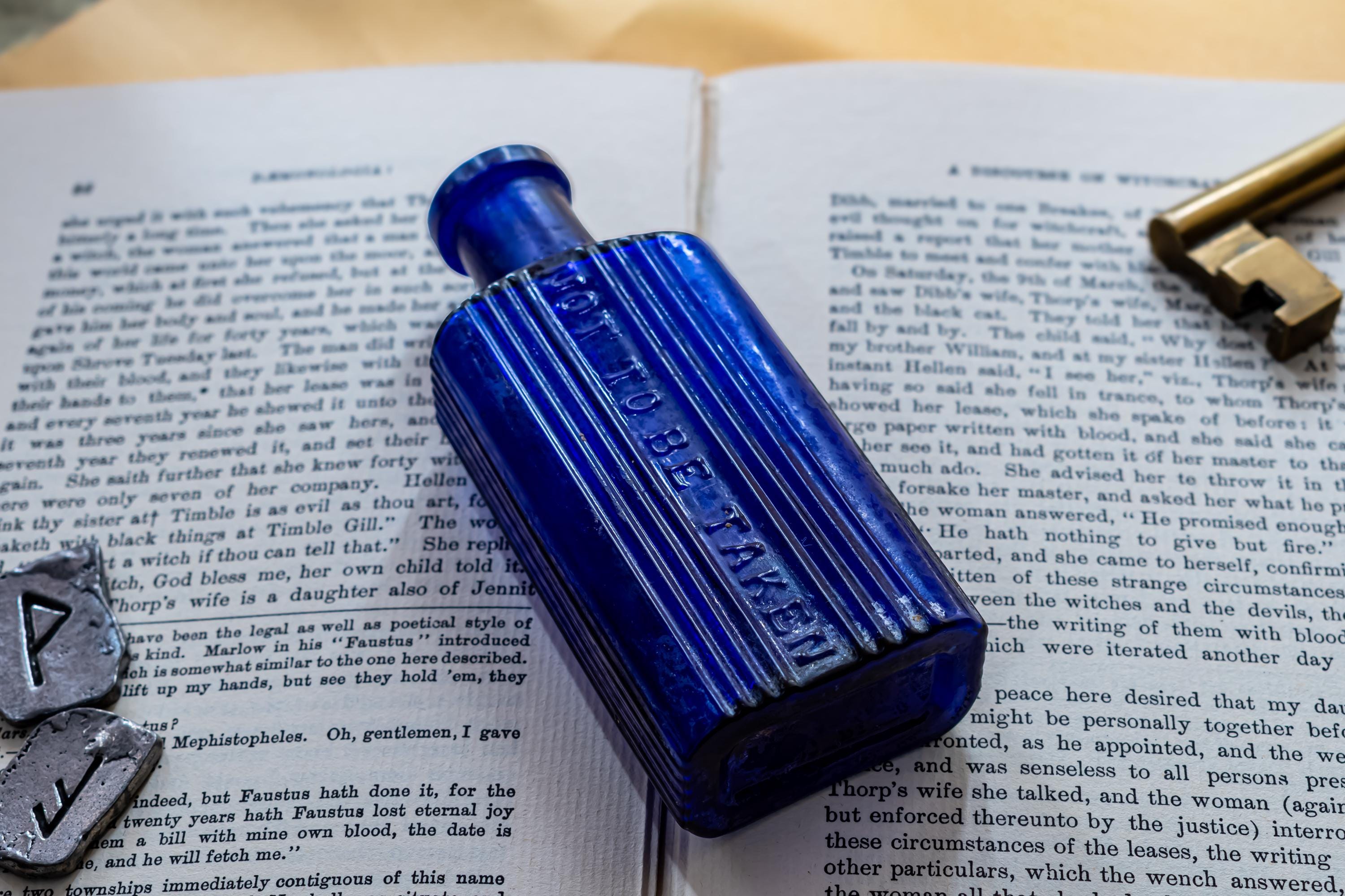 Antique cobalt blue ribbed glass poison bottle on top of a dark vintage book