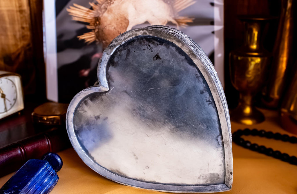 A solid sterling silver hand engraved jewelry box showing the bottom of the box. The shape of the jewelry box is a hard. It has engravings on the top and on the sides.