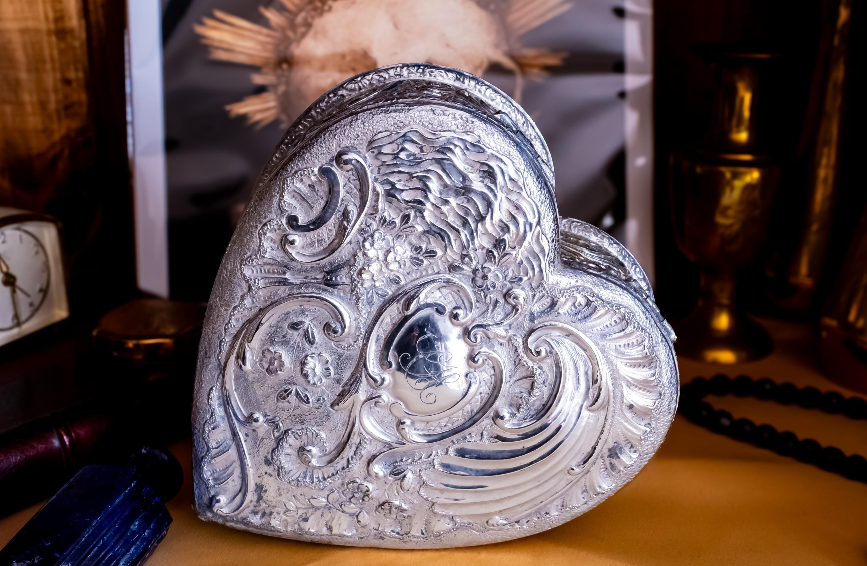 A solid sterling silver hand engraved jewelry box. The shape of the jewelry box is a hard. The box is laying on its side to showcase the engravings of the lid.