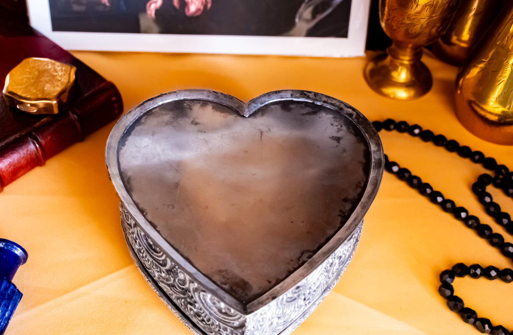 A solid sterling silver hand engraved jewelry box showing the bottom of the box. The shape of the jewelry box is a hard. It has engravings on the top and on the sides.