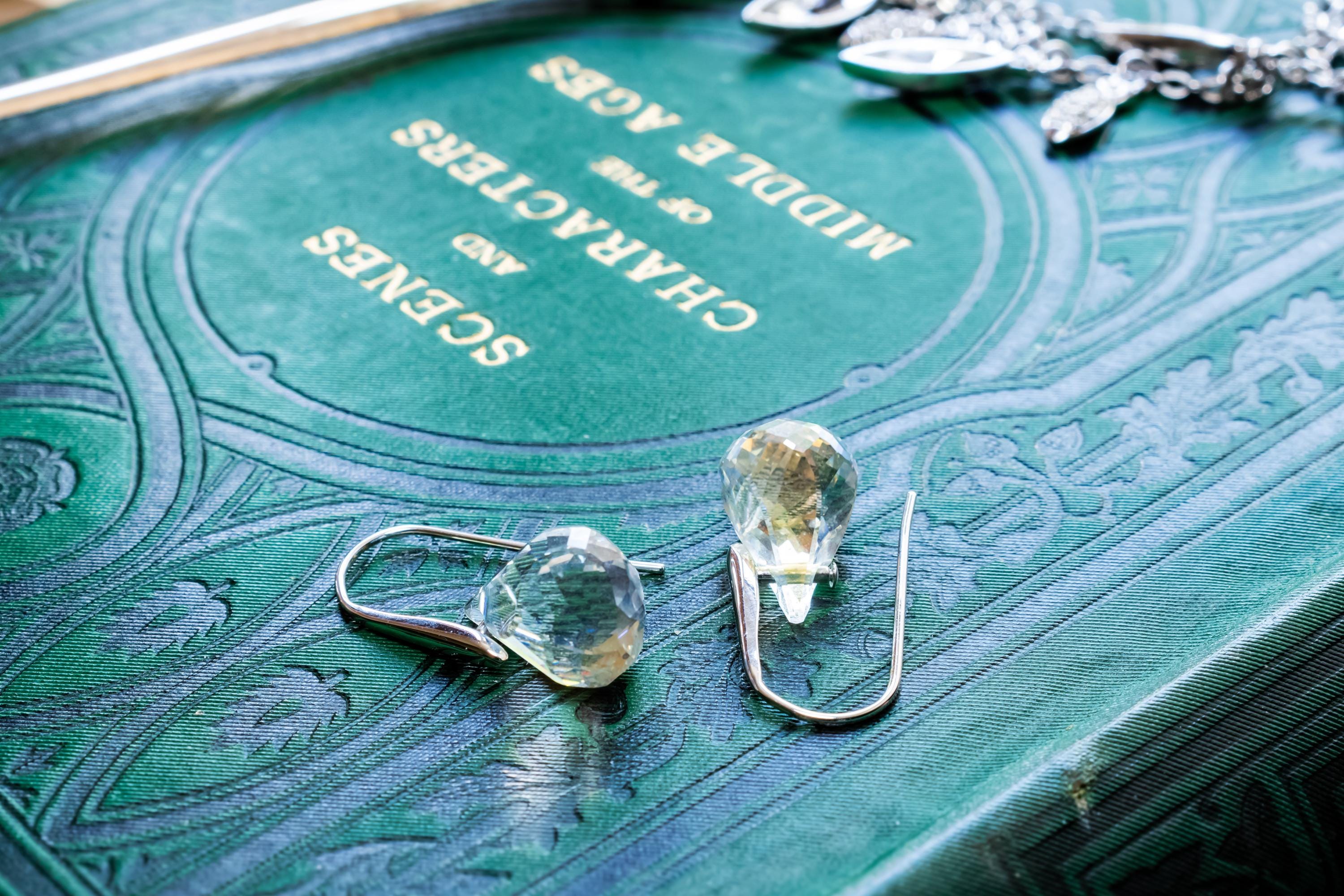 Vintage silver-tone Swarovski crystal necklace featuring round and marquise cut rhinestones, paired with matching crystal stud earrings, resting on a green antique book.