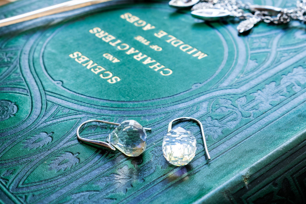 Vintage silver-tone Swarovski crystal necklace featuring round and marquise cut rhinestones, paired with matching crystal stud earrings, resting on a green antique book.