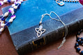 a vintage 925 sterling silver pendant necklace featuring a Celtic triquetra knot and a glowing oval moonstone cabochon, resting elegantly on a blue book cover.