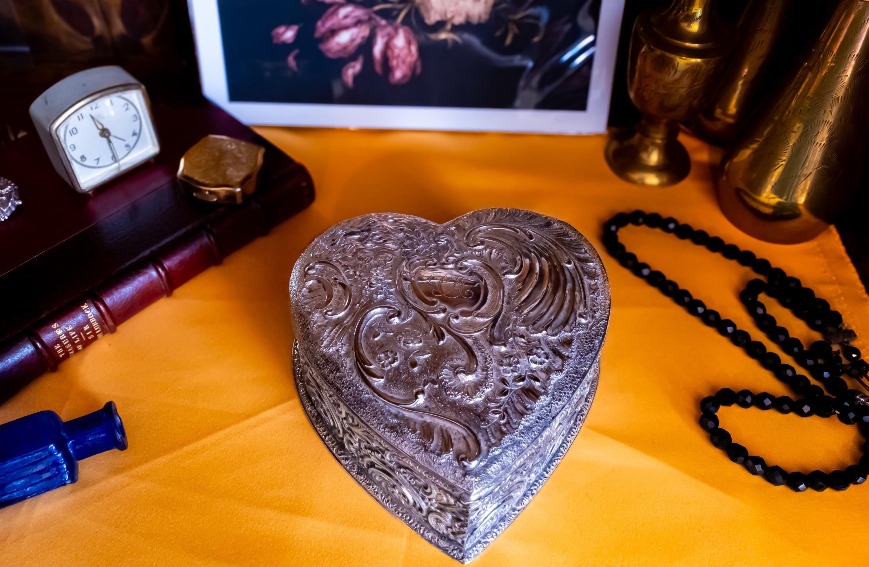 A solid sterling silver hand engraved jewelry box. The shape of the jewelry box is a hard. It has engravings on the top and on the sides.