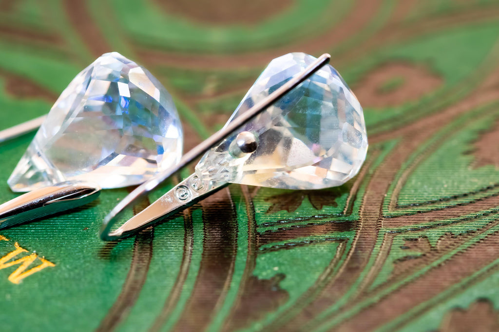 Vintage silver-tone Swarovski earrings, resting on a green antique book.
