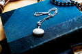 Miniature Victorian sterling silver perfume vial necklace. The antique poison bottle pendant features intricate botanical engravings and an unscrewed threaded cap with the original silver dauber wand attached