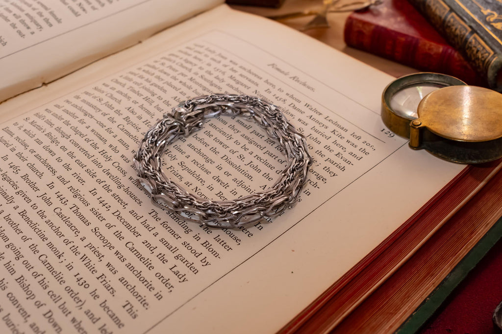 Heavy vintage sterling silver bracelet featuring a thick, intricately woven Byzantine chain link design and a secure clasp, resting on a vintage text.