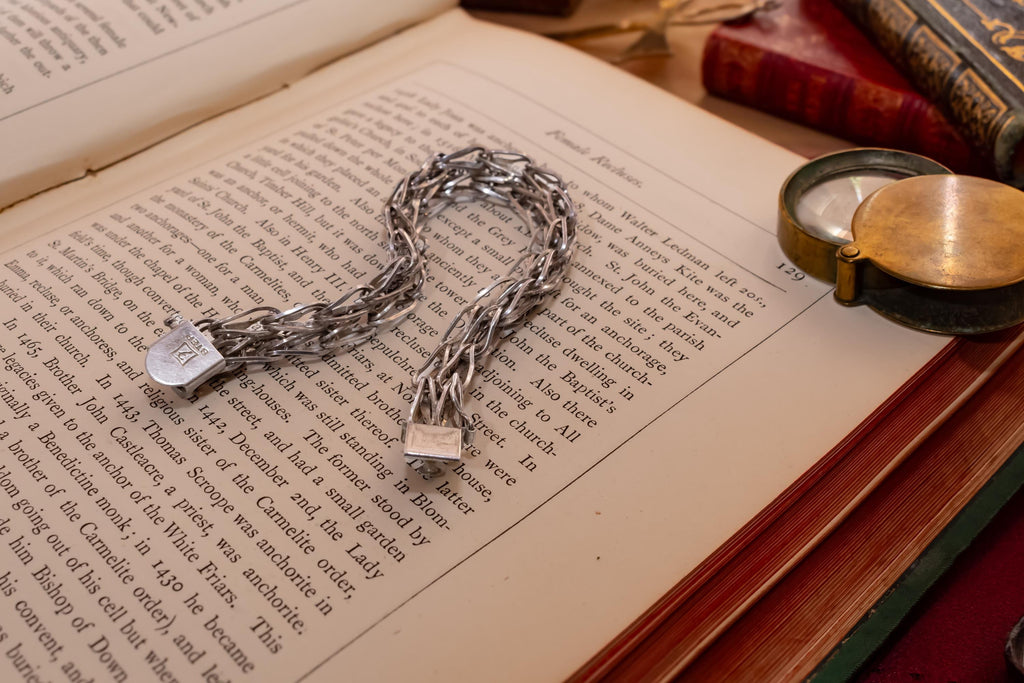 Heavy vintage sterling silver bracelet featuring a thick, intricately woven Byzantine chain link design and a secure clasp, resting on a vintage text.