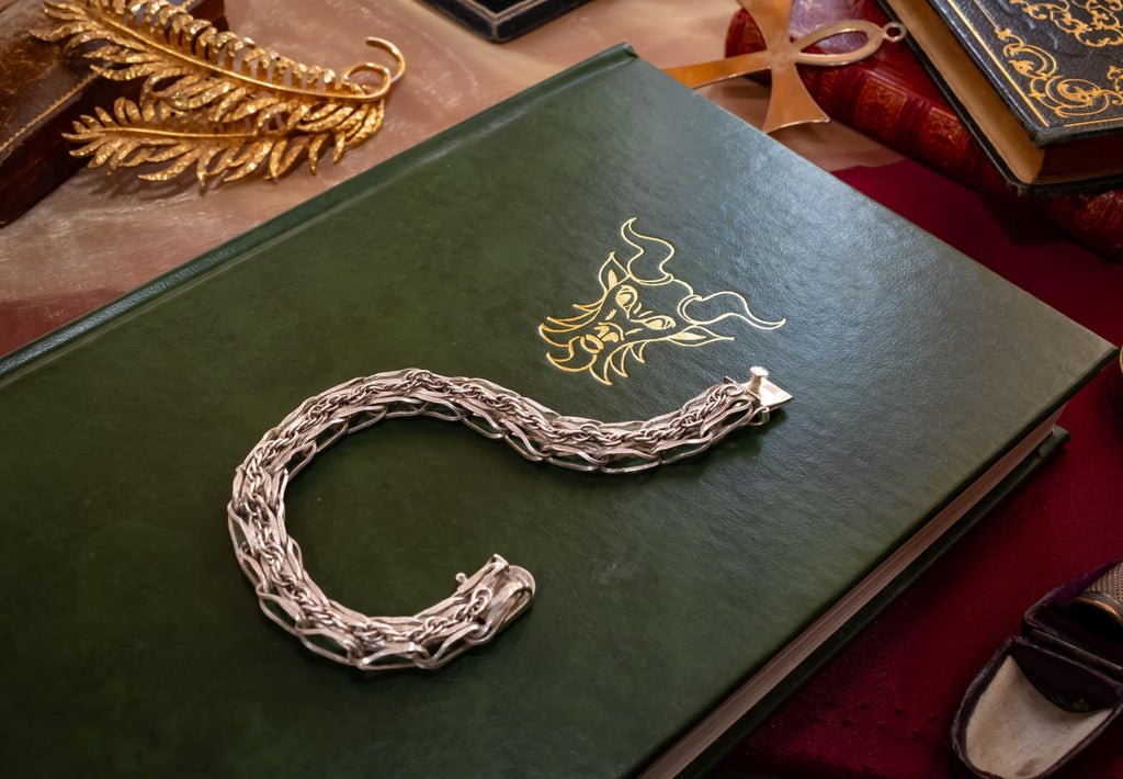 Heavy vintage sterling silver bracelet featuring a thick, intricately woven Byzantine chain link design and a secure clasp, resting on a vintage text.