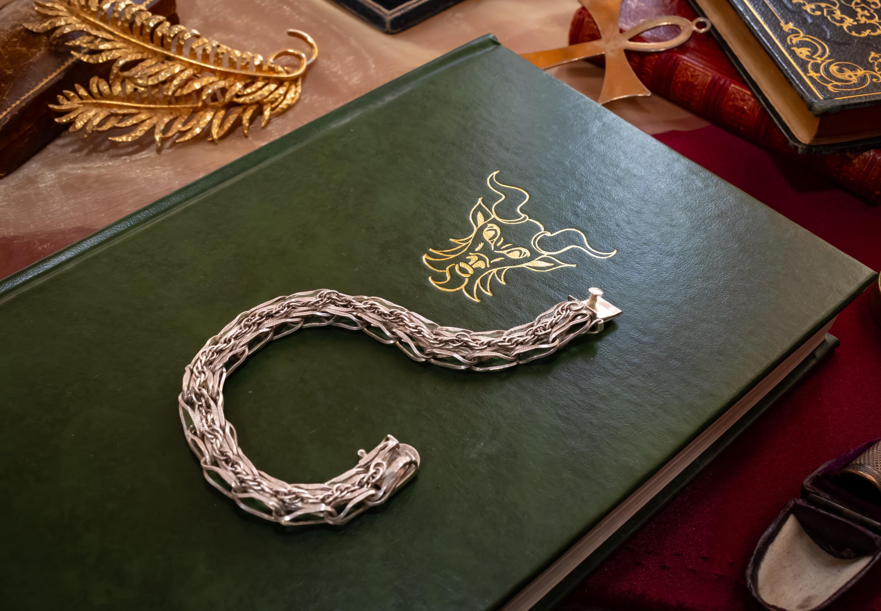Heavy vintage sterling silver bracelet featuring a thick, intricately woven Byzantine chain link design and a secure clasp, resting on a vintage text.