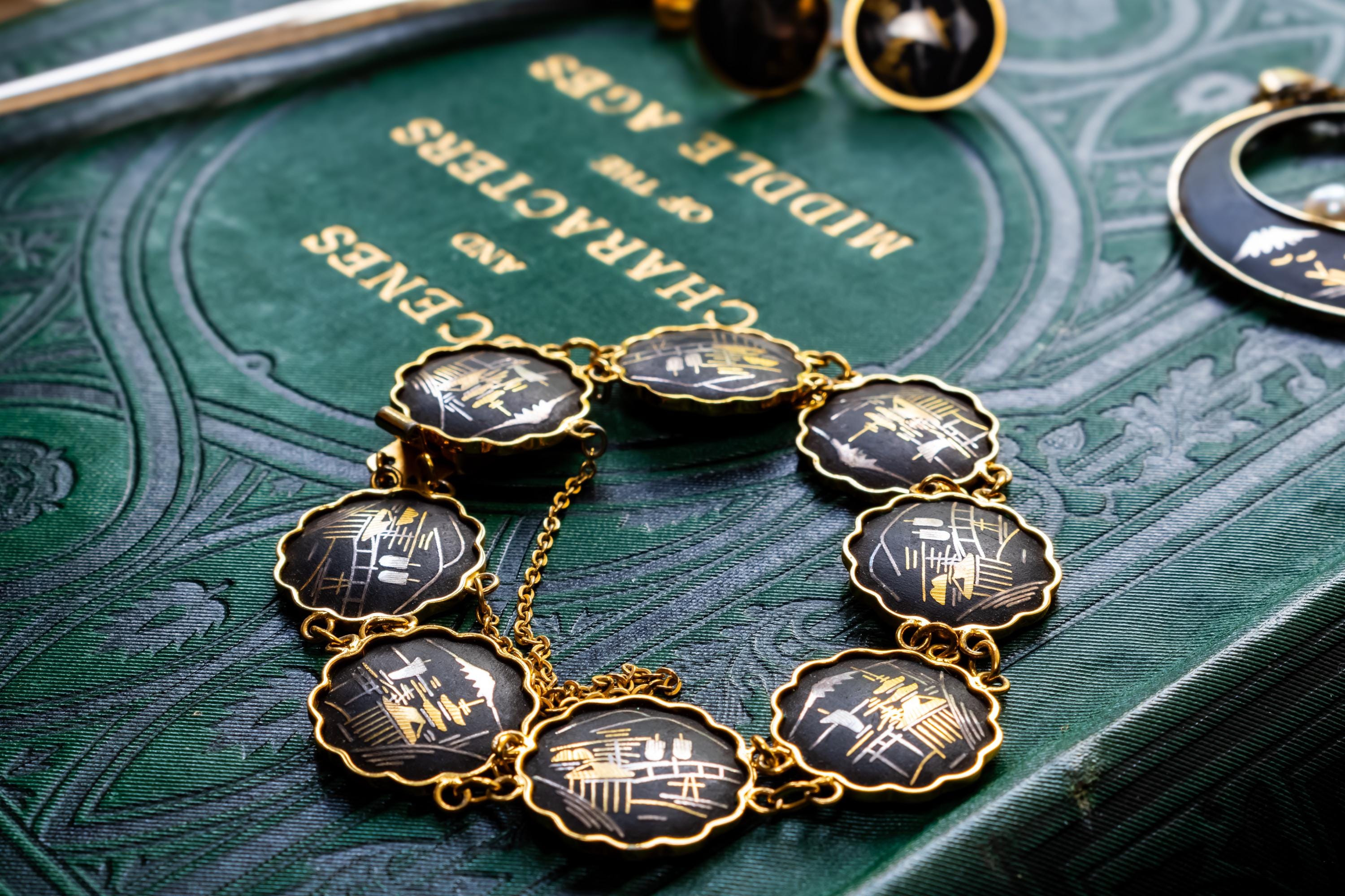 Vintage Amita Japanese damascene jewelry set including a necklace, bracelet, and earrings featuring black backgrounds with 24K gold inlay landscape scenes.