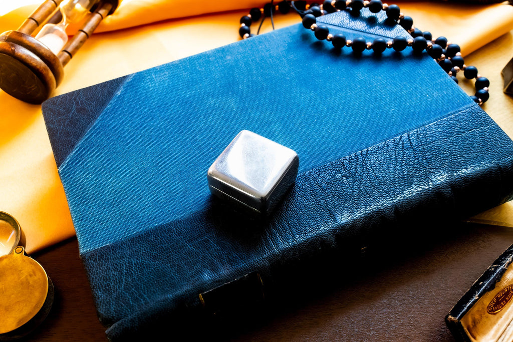 Vintage 2000 Birmingham silver square pill box featuring a smooth finish and a millennium stamp, resting on a blue antique book.