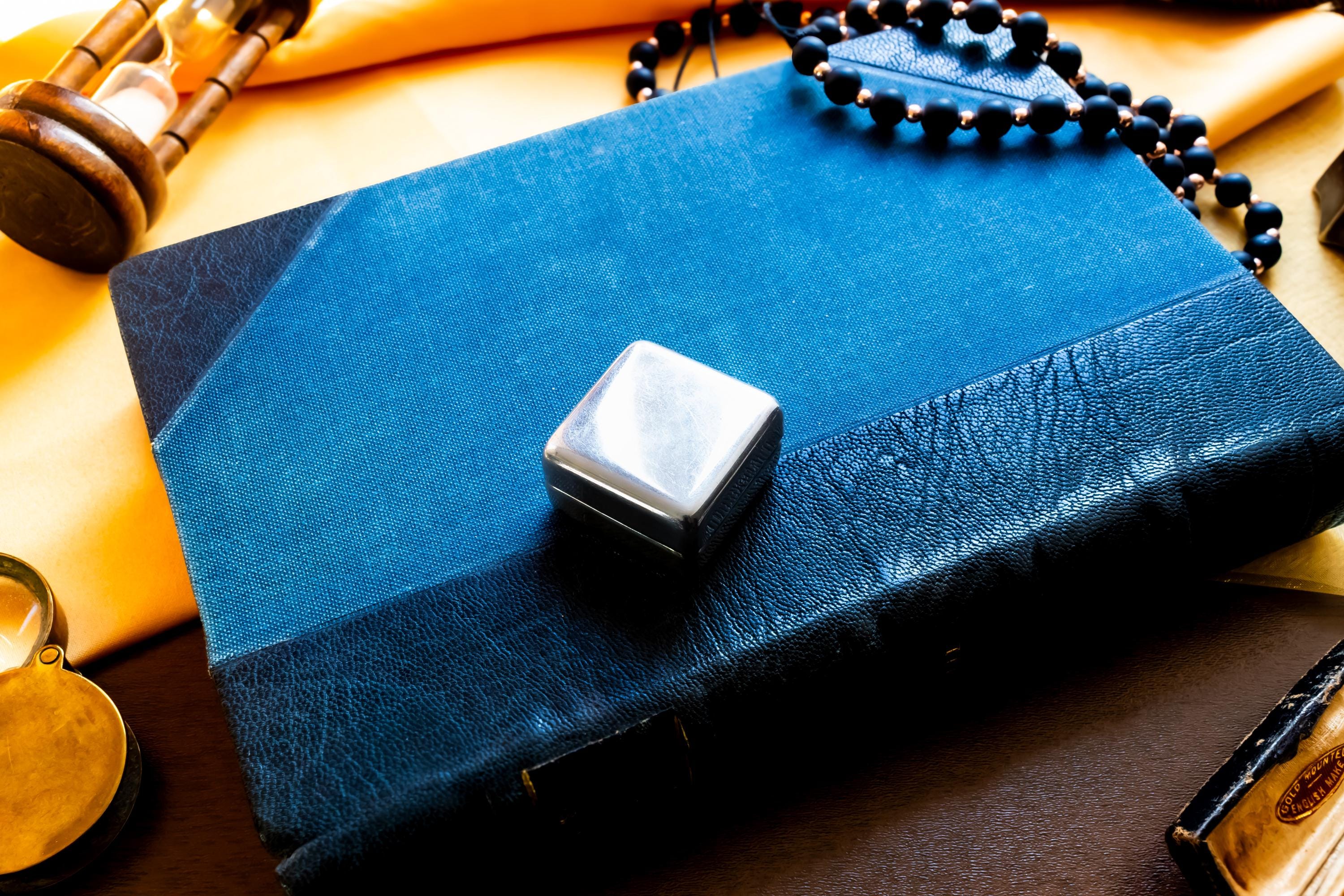 Vintage 2000 Birmingham silver square pill box featuring a smooth finish and a millennium stamp, resting on a blue antique book.