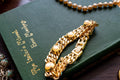 Substantial vintage chunky gold-tone curb link bracelet adorned with large faux pearls in heavy settings, resting on a green vintage book.