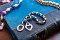 Vintage chunky sterling silver link bracelet featuring a heart charm and a toggle clasp closure, resting on an antique blue book.