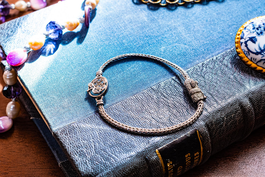 Vintage 800 silver woven bracelet featuring a central apple charm detailed with sparkling pave crystals, displayed on a blue antique text.