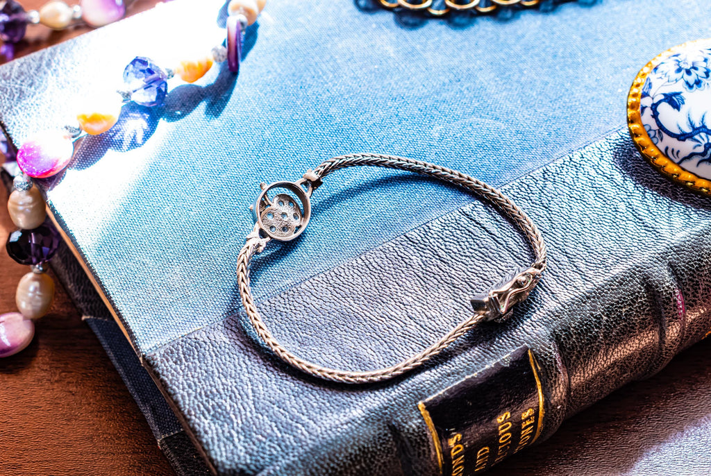 Vintage 800 silver woven bracelet featuring a central apple charm detailed with sparkling pave crystals, displayed on a blue antique text.