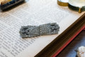 A silver-toned Art Deco brooch with intricate crystal or diamond inlay, resting on an open vintage book.