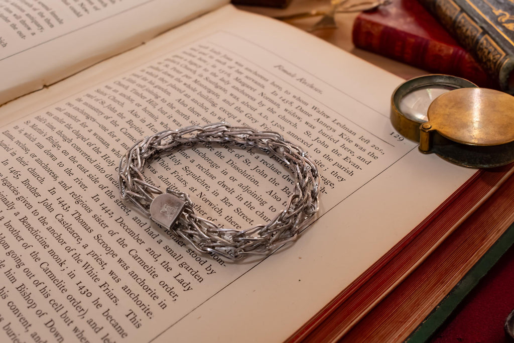 Heavy vintage sterling silver bracelet featuring a thick, intricately woven Byzantine chain link design and a secure clasp, resting on a vintage text.