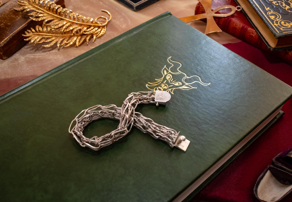 Heavy vintage sterling silver bracelet featuring a thick, intricately woven Byzantine chain link design and a secure clasp, resting on a vintage text.