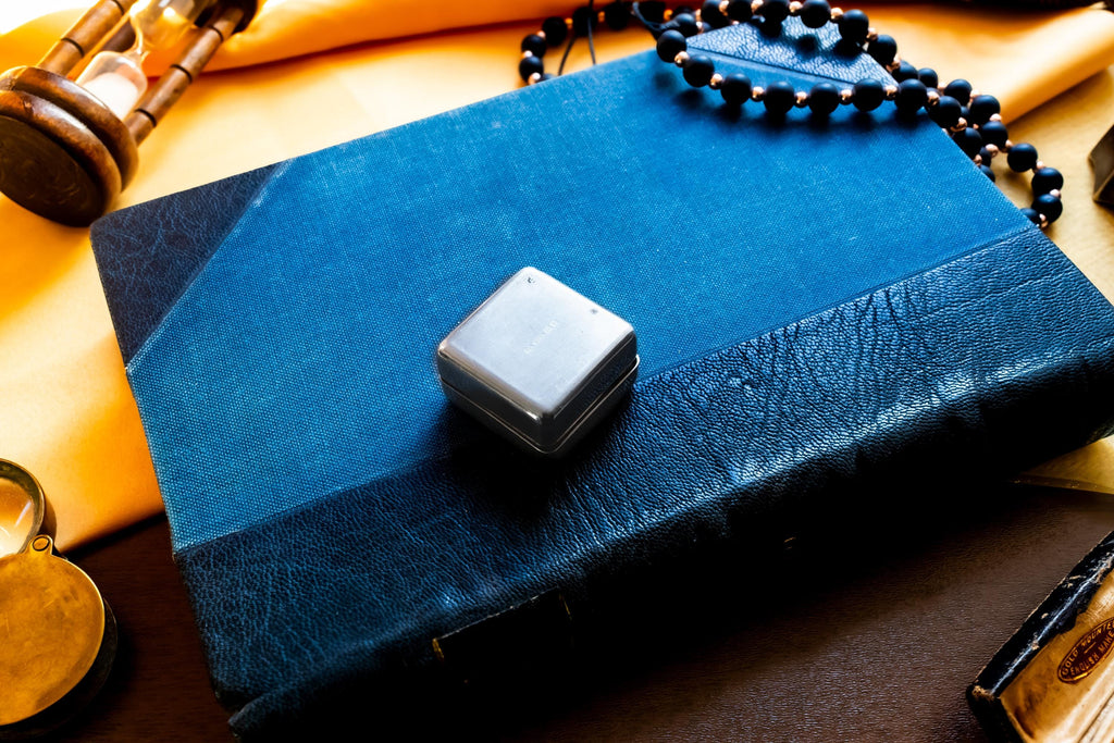 Vintage 2000 Birmingham silver square pill box featuring a smooth finish and a millennium stamp, resting on a blue antique book.