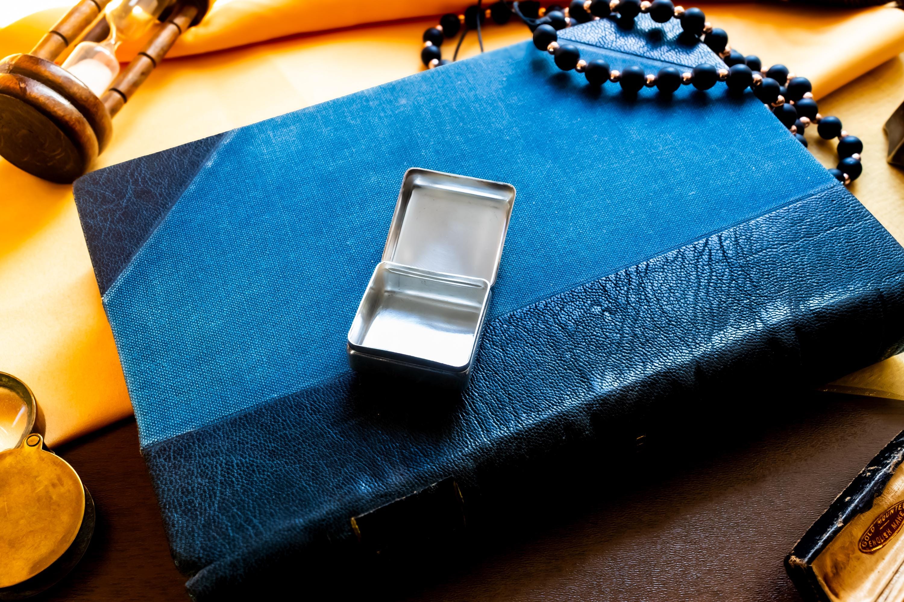 Vintage 2000 Birmingham silver square pill box featuring a smooth finish and a millennium stamp, resting on a blue antique book.
