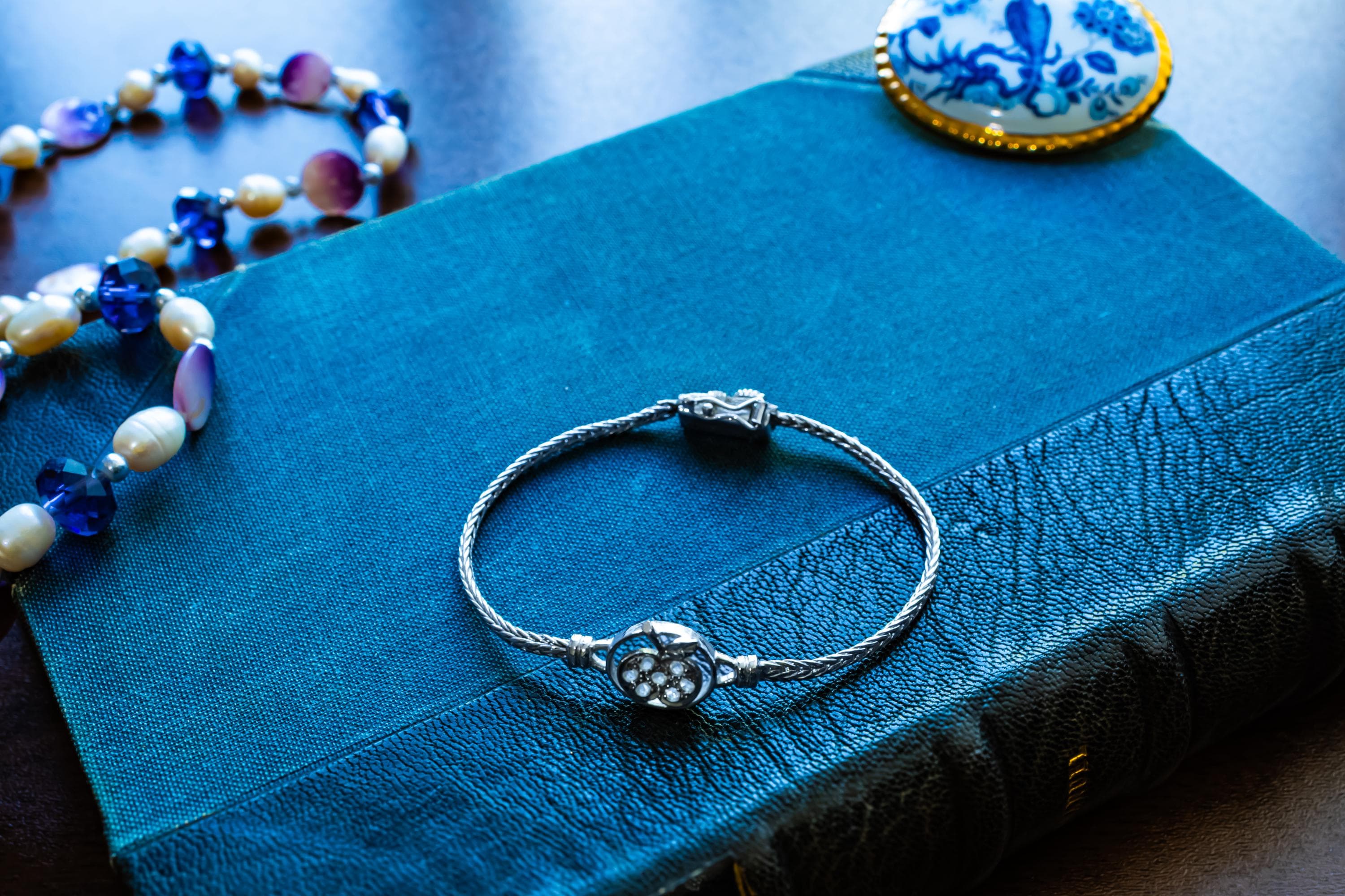 Vintage 800 silver woven bracelet featuring a central apple charm detailed with sparkling pave crystals, displayed on a blue antique text.