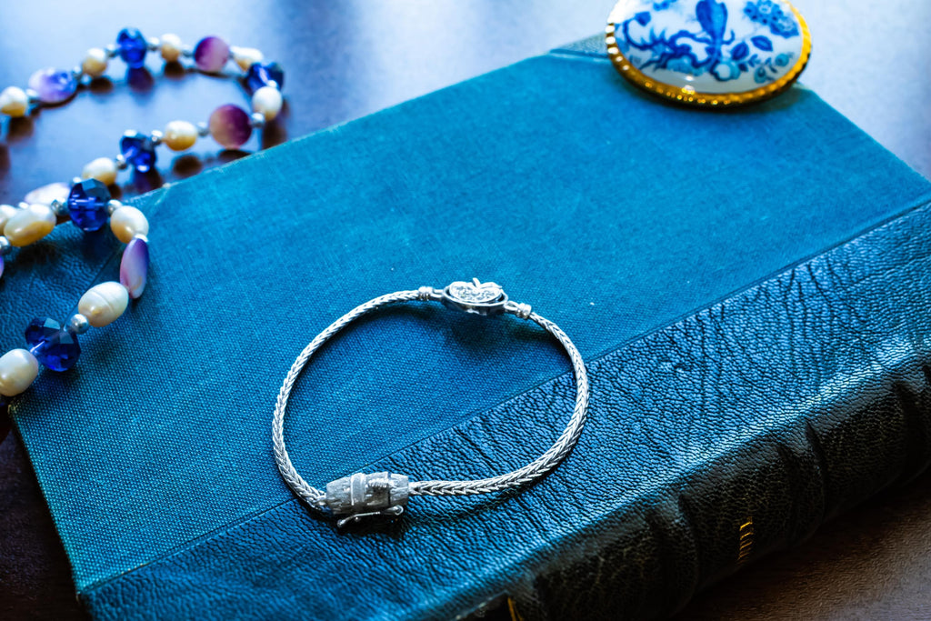 Vintage 800 silver woven bracelet featuring a central apple charm detailed with sparkling pave crystals, displayed on a blue antique text.